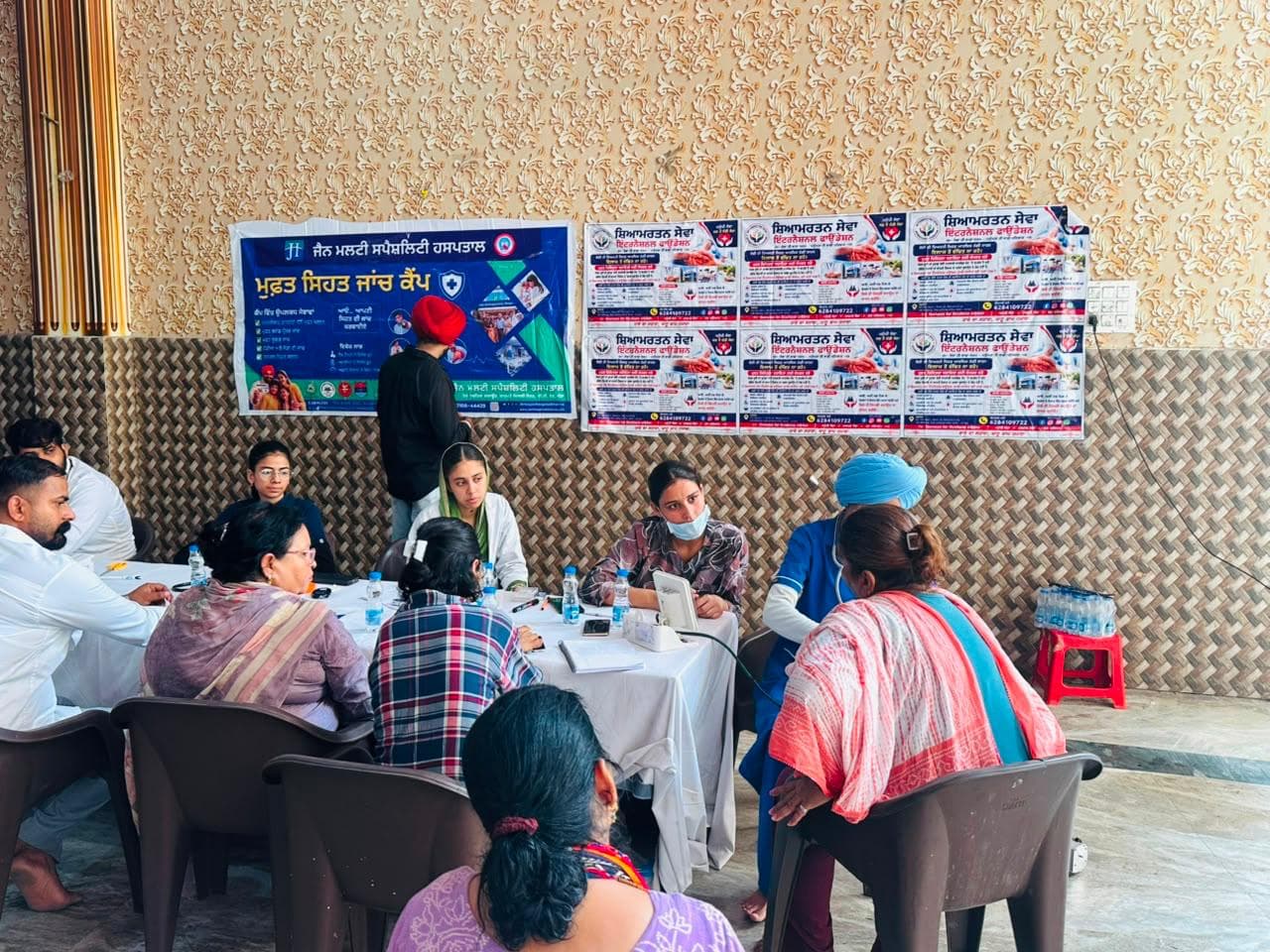 ਸੇਵਾ ਮੇਜ਼ ਉੱਤੇ ਵਸਨੀਕਾਂ ਦੀ ਮਦਦ ਕਰਦੇ ਸਵੈਸੇਵਕਾਂ ਨਾਲ ਭਾਈਚਾਰਕ ਸਿਹਤ ਜਾਂਚ।